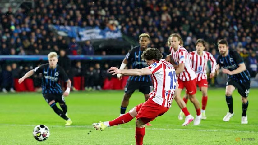 Julian Álvarez (19) strikes the ball cleanly to score a penalty for Atlético Madrid while Club Brugge defenders watch on.