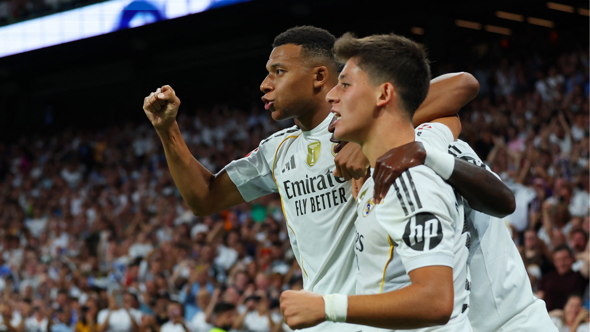 Kylian Mbappe smiles and shakes hands with Dani Ceballos while Eduardo Camavinga looks on after Real Madrid's victory.